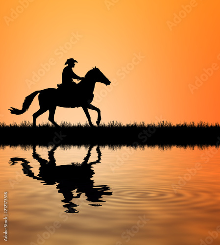 silhouette Cowboy riding a horse and water reflection on sunrise © rathchapon