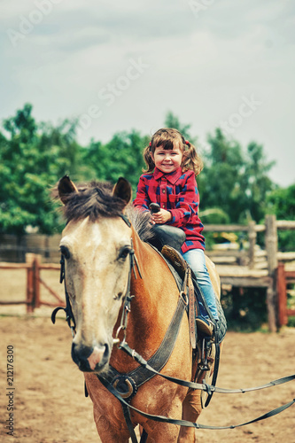 A little girl is trained to ride a horse