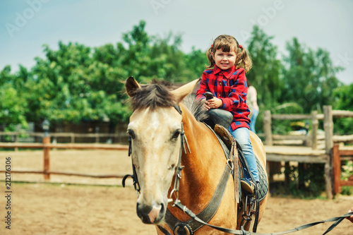 A little girl is trained to ride a horse