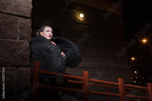 Woman with black wings in night city