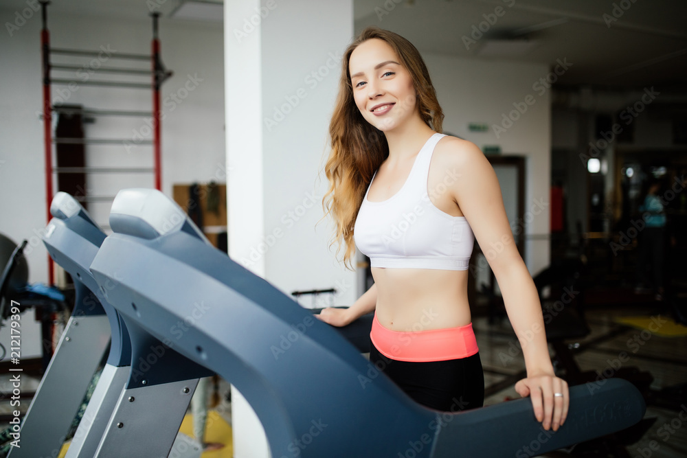 Side view of sporty woman exercising on treadmill in gym Side view of sporty woman exercising on treadmill in gym