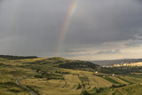 Beautiful rainbow over hills over the town and green hills