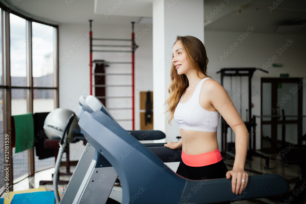 Side view of sporty woman exercising on treadmill in gym Side view of sporty woman exercising on treadmill in gym