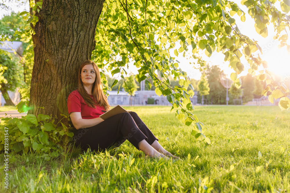 Girl sitting in the summer park and planning her goals and ways with notes. Life coach goals concept Girl sitting in the summer park and planning her goals and ways with notes. Life coach goals concept