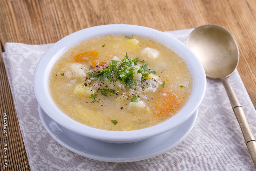 Fresh vegetable soup made of carrot, potato, cauliflower, parsley and rice in white plate, Fresh vegetable soup made of carrot, potato, cauliflower, parsley and rice in white plate,