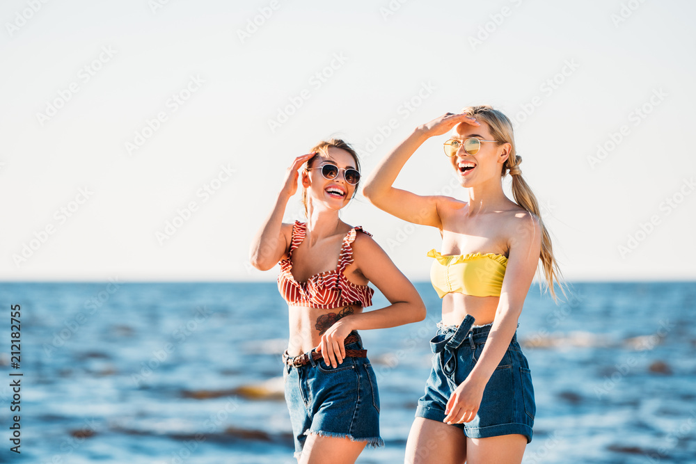 happy young women in sunglasses walking together on beach happy young women in sunglasses walking together on beach