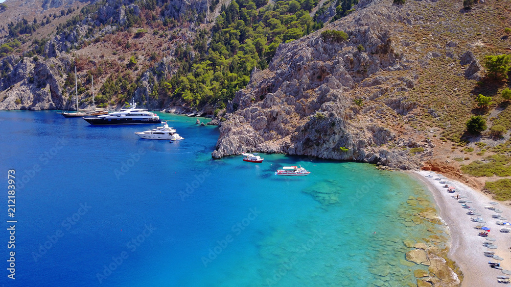 Aerial birds eye view photo taken by drone of famous tropical rocky beach of Nannou with yachts docked and clear turquoise waters, Symi island, Dodecanese, Greece