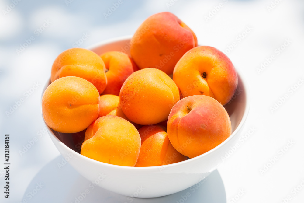 Apricots in a white bowl on white background Apricots in a white bowl on white background
