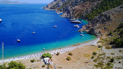 Aerial birds eye view photo taken by drone of famous tropical rocky beach of Nannou with yachts docked and clear turquoise waters, Symi island, Dodecanese, Greece © aerial-drone