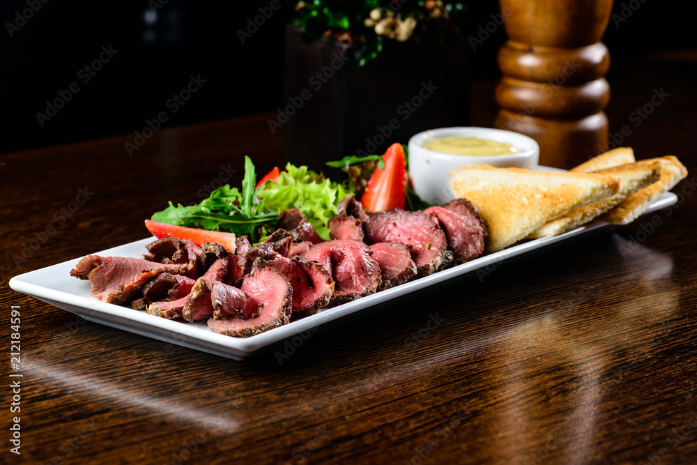 Juicy meat slices served with toasts and sauce in restaurant