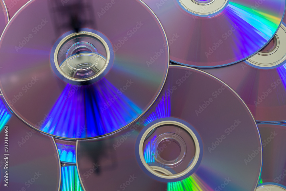DVDs, digital optical disk storage. Group of DVDs and its characteristic light DVDs, digital optical disk storage. Group of DVDs and its characteristic light