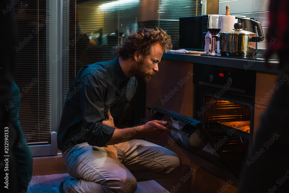 Guy opened the oven and looks whether the dish is ready Guy opened the oven and looks whether the dish is ready