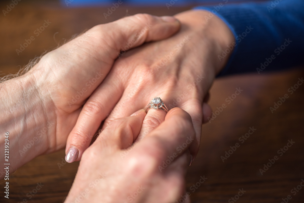 Man putting a ring on woman's finger