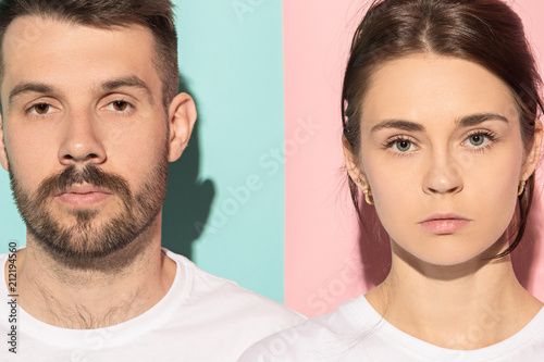 The serious man and woman looking at camera against pink and blue background.