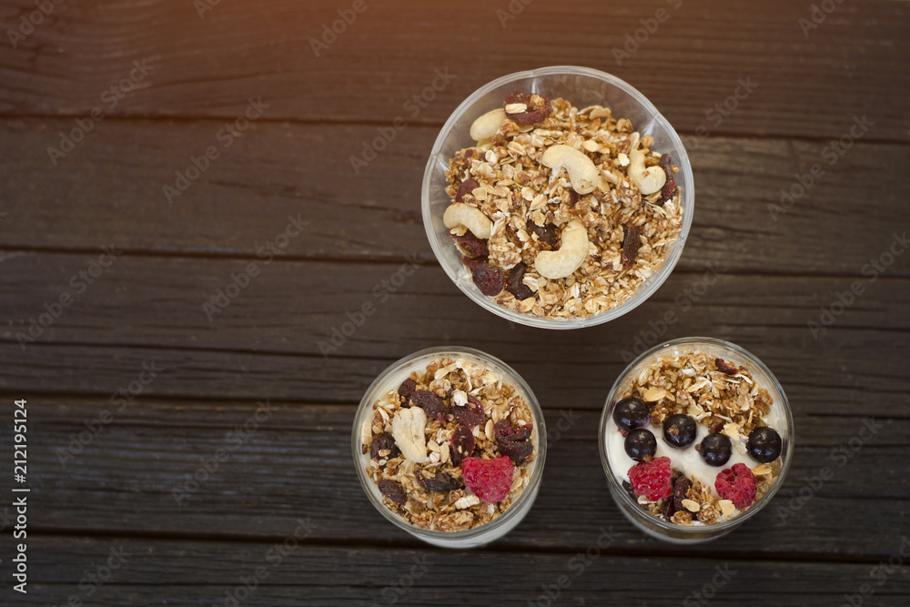 Granola with cashew in a cup with yoghurt. Dark wooden background