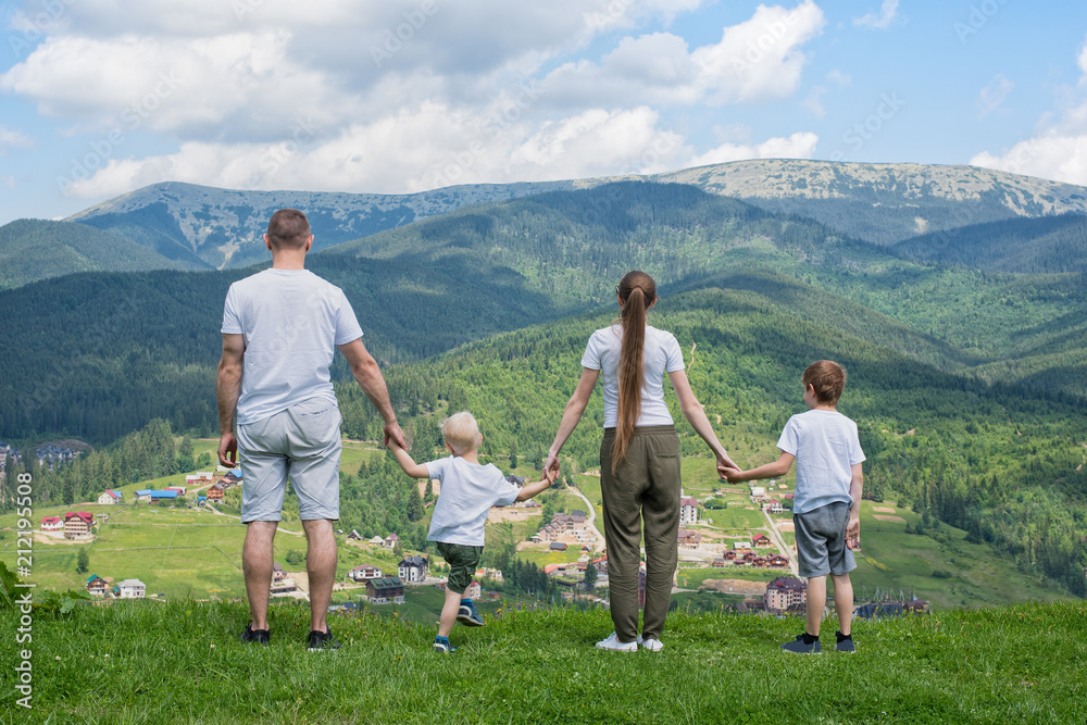 Family holiday. Parents and two sons admire views of the valley. Mountains in the distance. Back view