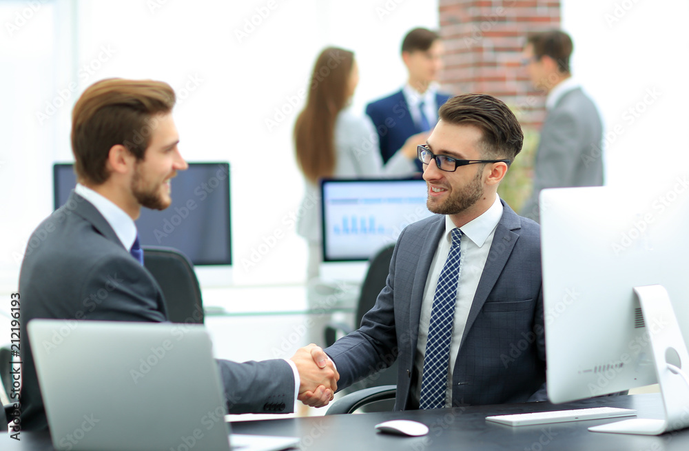 Successful managers shaking hands after closing deal in office Successful managers shaking hands after closing deal in office