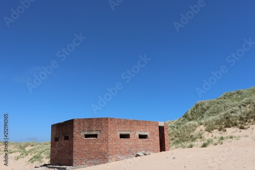 World War 2 anti-aircraft gun shelter on beach against blue sky with copy space