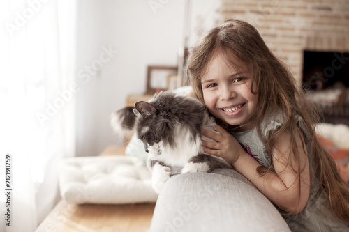 little girl and cat at home on the couch. A happy child and a pet. Copy space