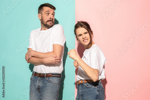 The young emotional angry woman on pink studio background photo
