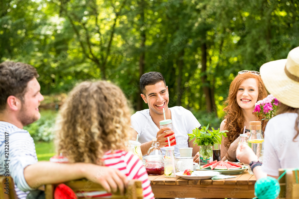 Happy friends sitting on the terrace on a sunny day and having fun together