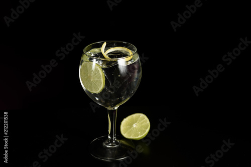 A glass of Gin Tonic cocktail drink with ice cubes and a slice of lime and twist of lemon, Isolated .