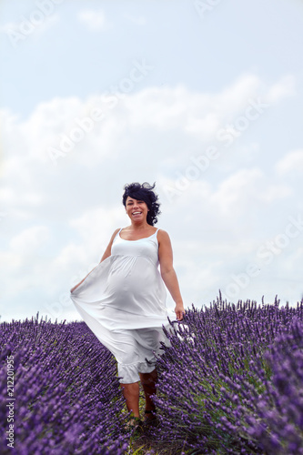 Fototapeta Naklejka Na Ścianę i Meble -  Happy pregnant woman is walking on the lavender field..