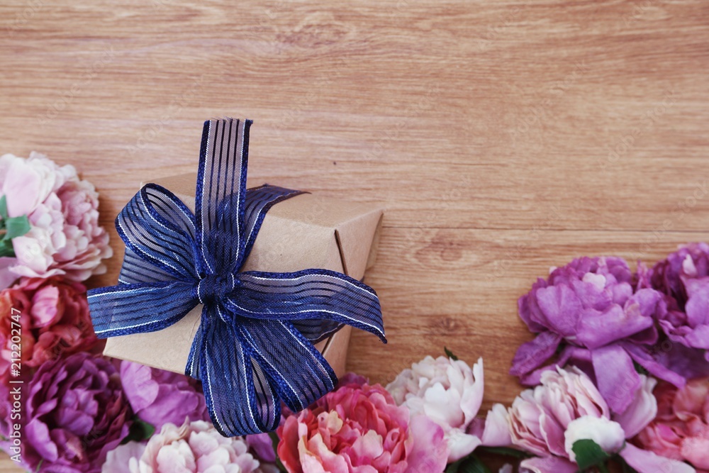 top view of gift box present with blue ribbon and  flower bouquet on space wooden background
