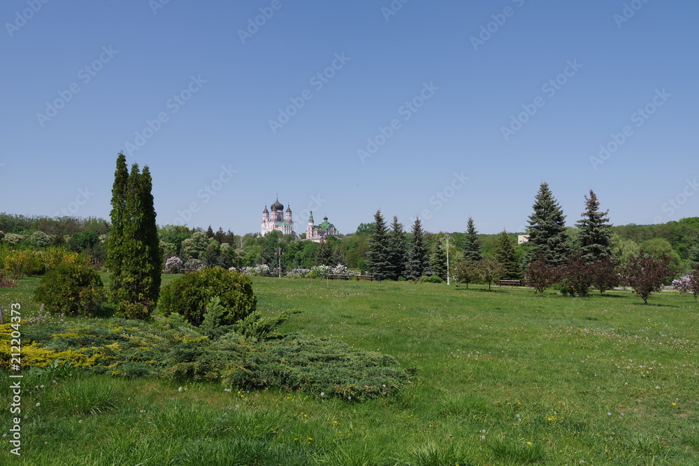 park with a green lawn and a monastery in the distance
