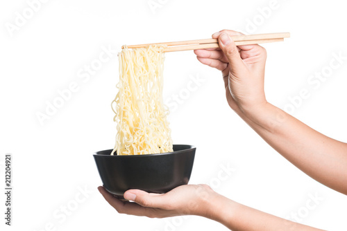 Instant noodles in black bowl with chopsticks on white background