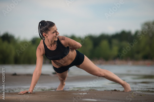 Cute woman doing push-ups on the beach against the sea