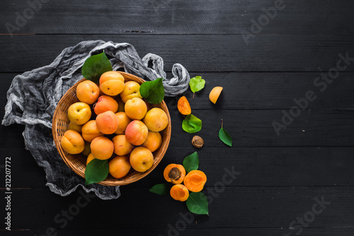 Sweet ripe apricots on black wooden background. Copy space