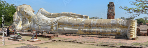 People praying in front of reclining Buddha at Ayutthaya, Thailand photo