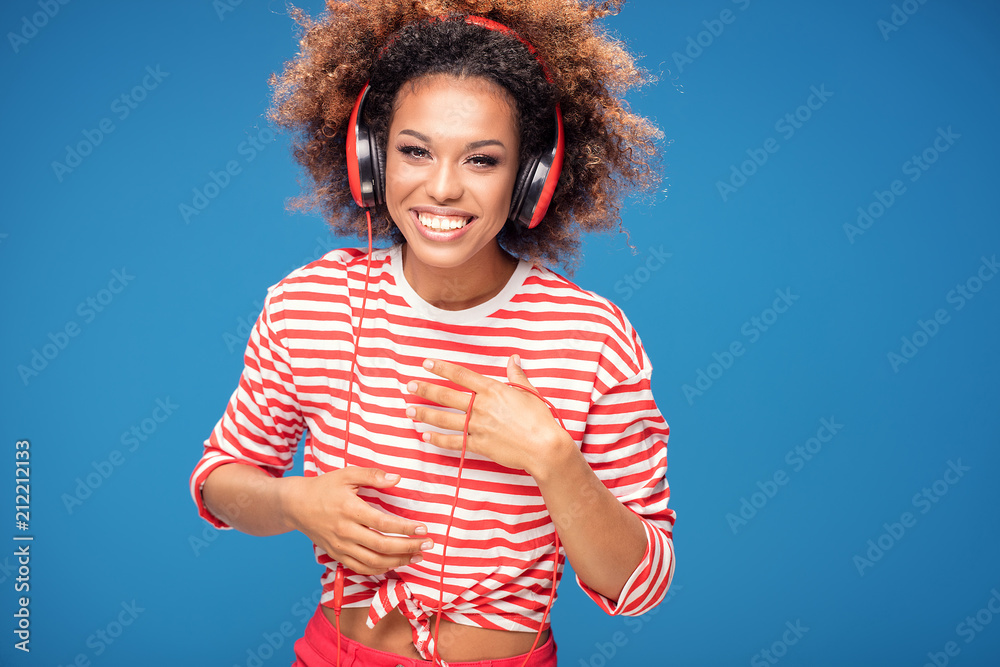 Adorable happy afro girl with red headphones laughing. Adorable happy afro girl with red headphones laughing.
