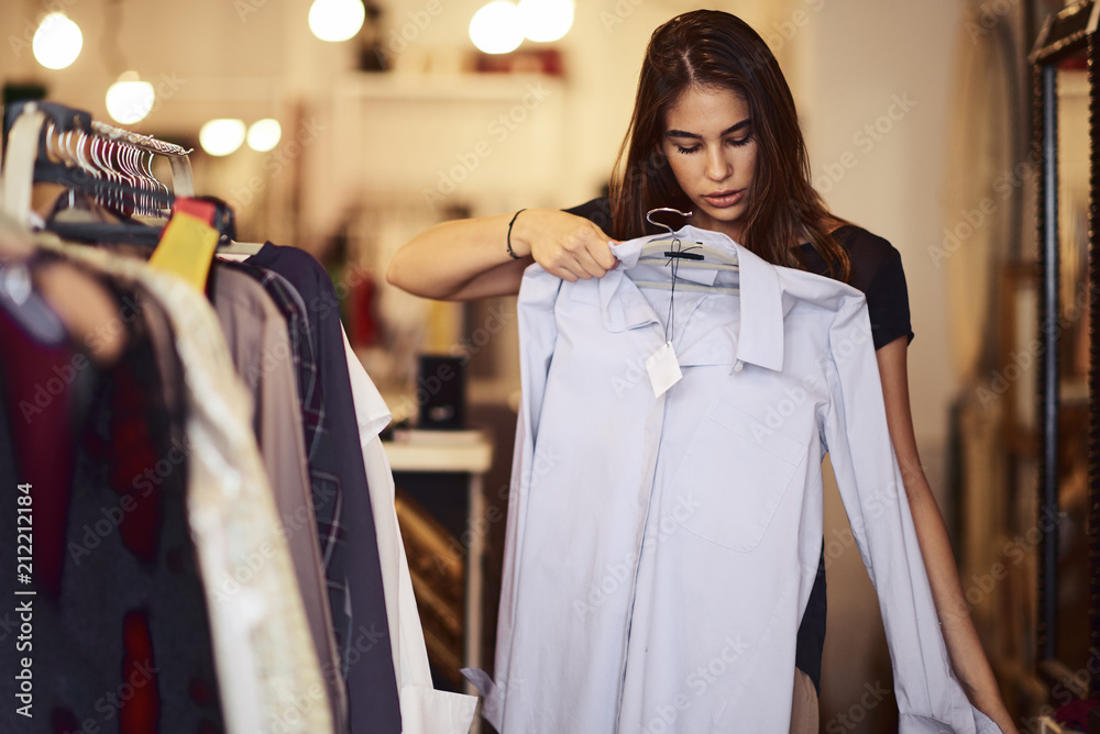 Woman trying on a shirt while standing in the store. Woman trying on a shirt while standing in the store.