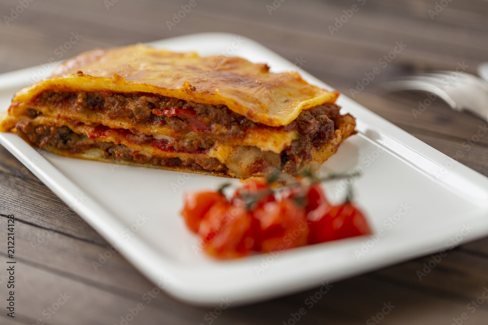 Tasty lasagne with meat covered with cheese served on white plate. Tasty lasagne with meat covered with cheese served on white plate.