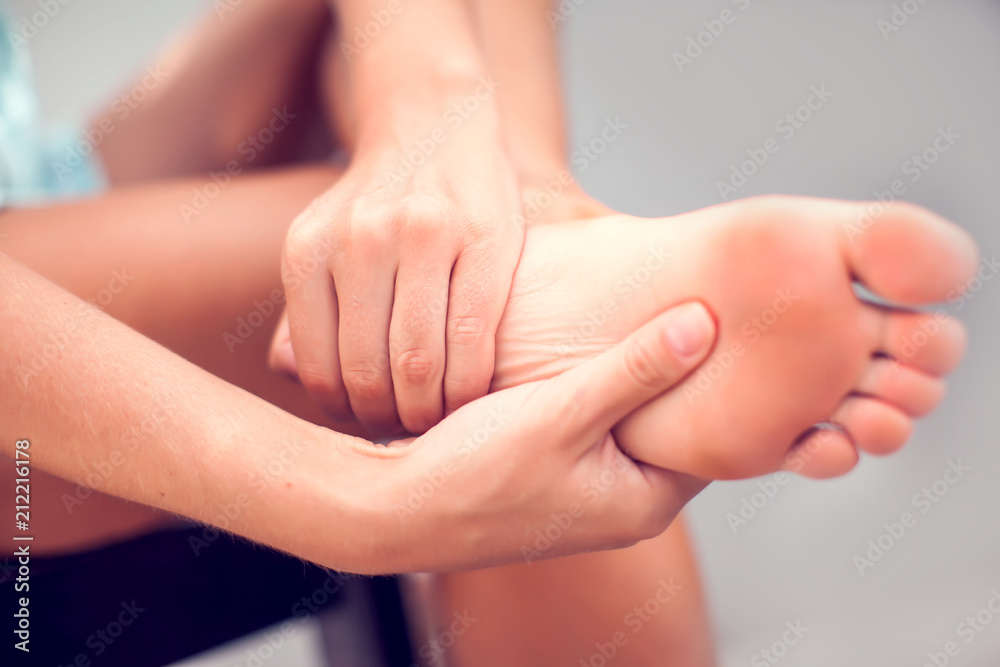 Woman hand holding foot with pain, health care and medical concept Woman hand holding foot with pain, health care and medical concept