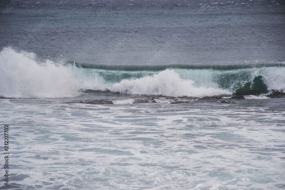 typical windy day in gran canaria, canary islands, spain. ideal for surfing, bigger waves in the sea, turquoise blue water in the ocean