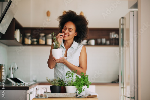 Beautiful mixed race woman smelling fresh sipces at kitchen.