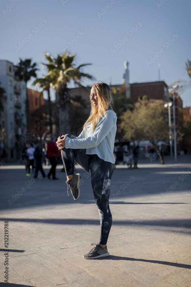 Spain, Barcelona, woman stretching leg on beach promenade Spain, Barcelona, woman stretching leg on beach promenade