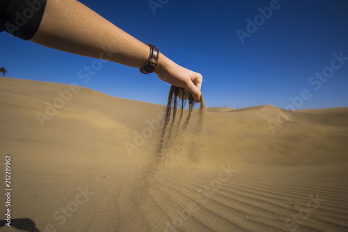 maspalomas dunes, gran canaria, spain - summer evening time, wind is blowing the sand up, woman hand holding sand and it is falling down