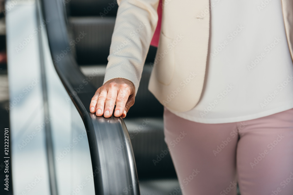 cropped image of woman on escalator in shopping mall cropped image of woman on escalator in shopping mall