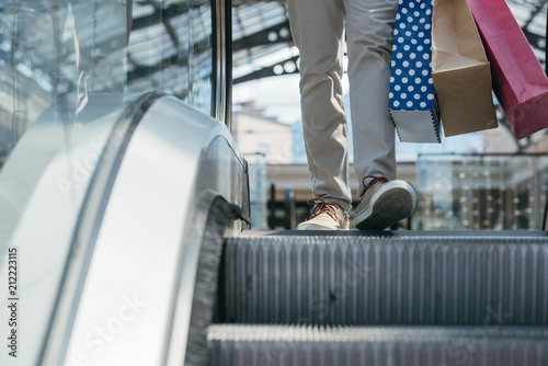 cropped image of man stepping on escalator in shopping mall