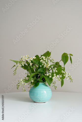 Branch of blossoming bird cherry stands in a round vase