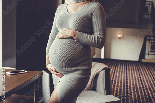 Pregnant woman in sexy dress holds hands on belly. photo