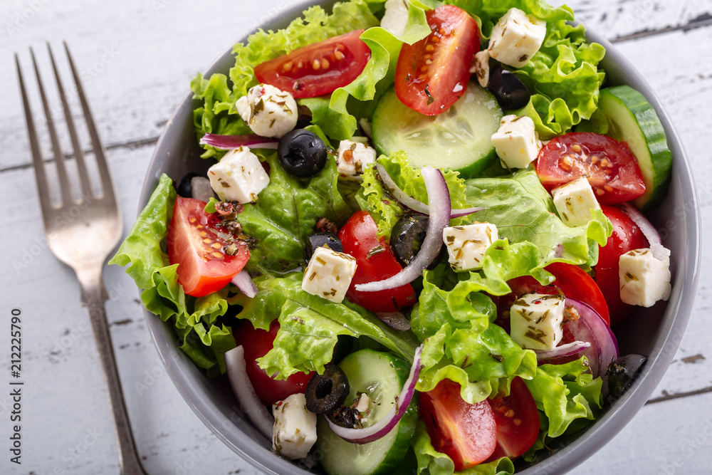 Fresh greek salad served in bowl with fork.