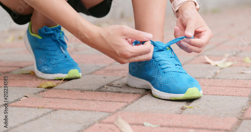 Woman fixing sport shoes lace at outdoor park