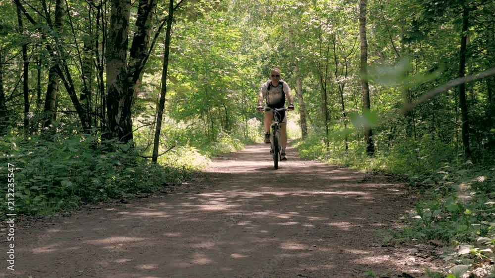 A man is training in the park. He rides a bicycle on a summer day, on special tracks. A man is training in the park. He rides a bicycle on a summer day, on special tracks.