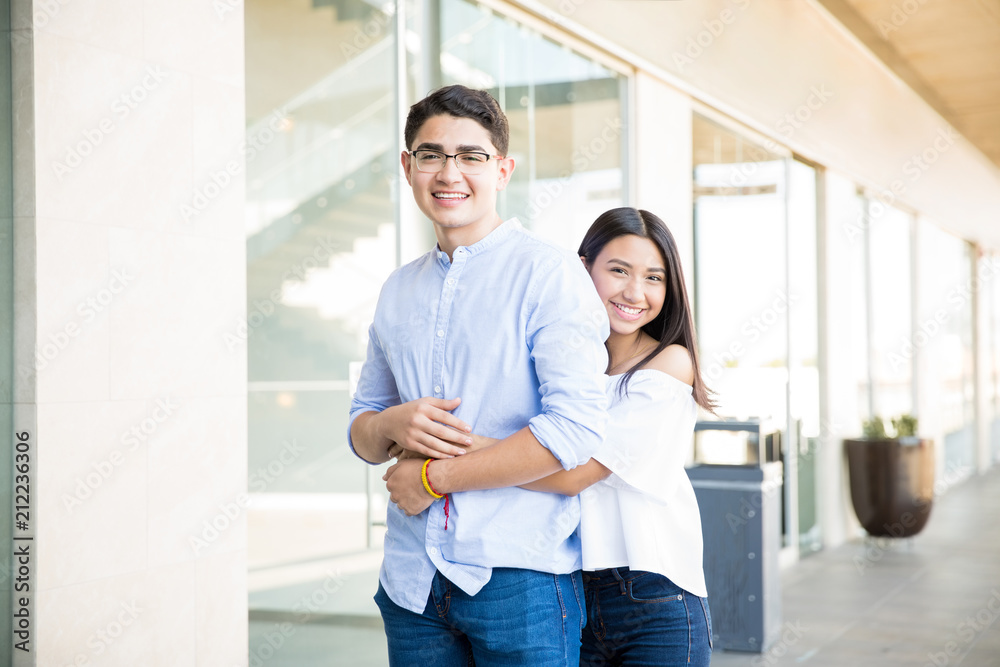 Teenage Girl Embracing Boy From Behind At Shopping Mall Teenage Girl Embracing Boy From Behind At Shopping Mall