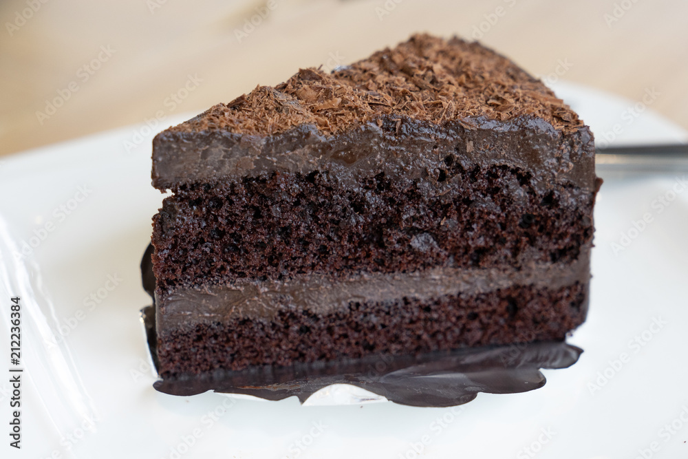 slice of chocolate cake, layer chocolate fudge on white plate, wooden table slice of chocolate cake, layer chocolate fudge on white plate, wooden table